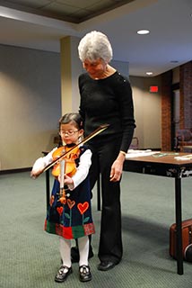 Photo: Young girl tries the violin for the first time.